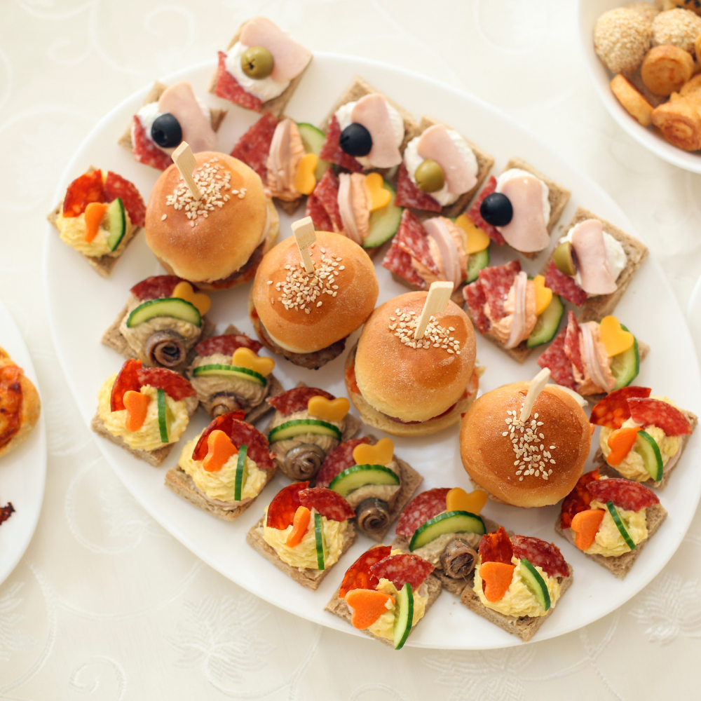 Plateau de canapés et mini sandwichs garnis : tartines avec œuf et olives, charcuterie, légumes frais, petits pains aux
