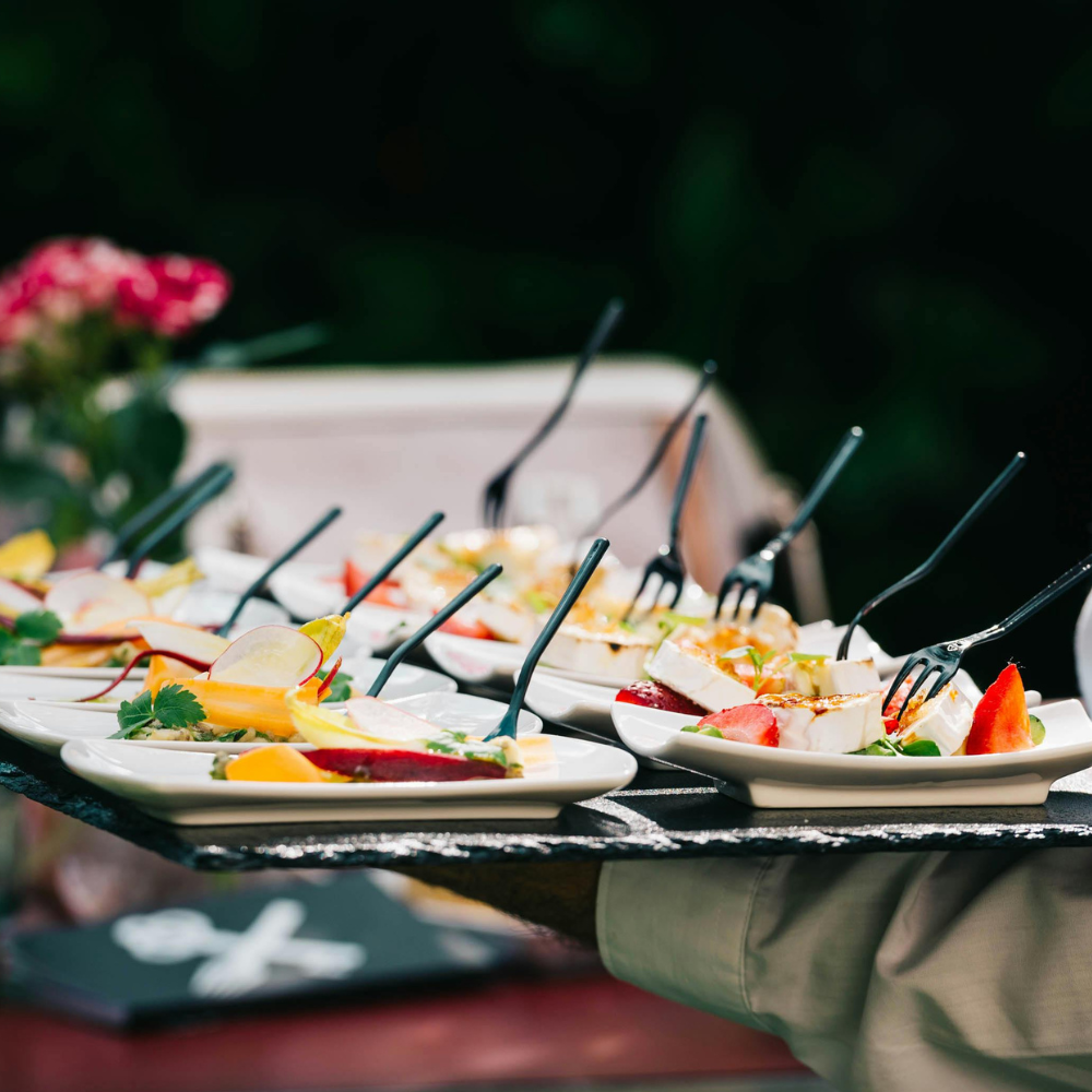 Assiettes de dégustation avec mozzarella, fruits frais et garnitures colorées présentées sur ardoise avec fourchettes